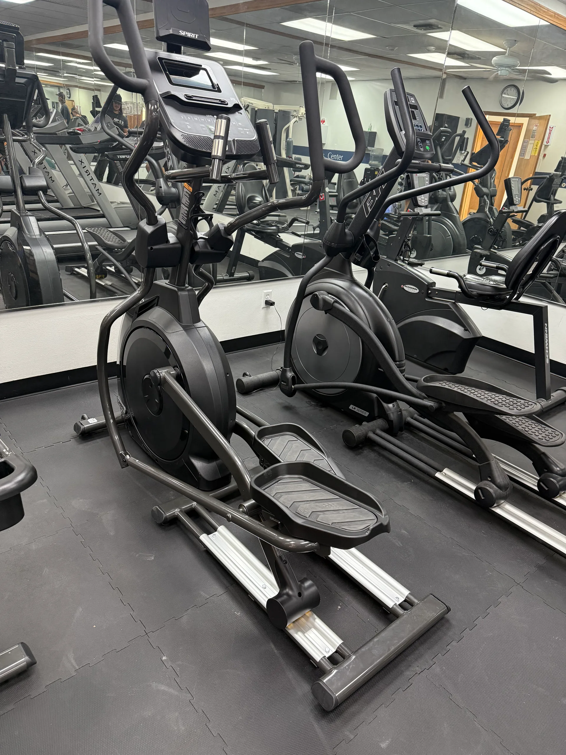 Elliptical trainers reflected in a full-length mirror wall