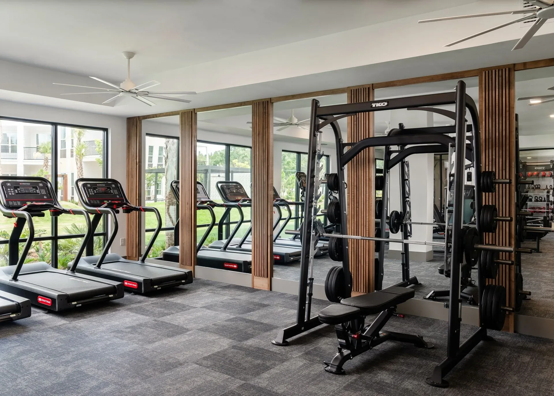 Treadmills and a Smith machine in a bright amenity gym