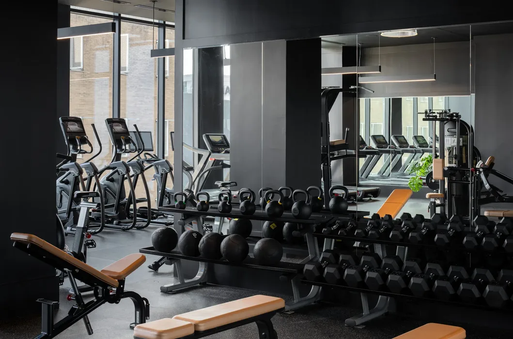 Dumbbell and kettlebell racks along a mirrored strength wall
