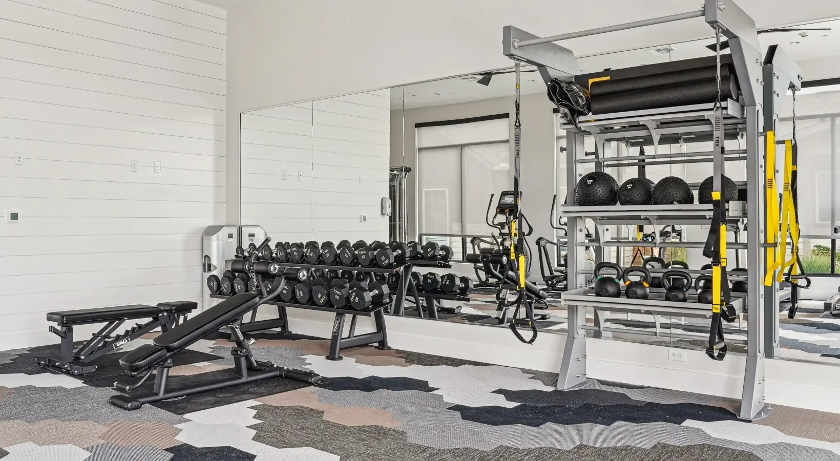 Dumbbell rack, kettlebells and TRX suspension trainers in a free-weight corner