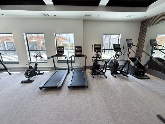Cardio row beneath a coffered ceiling in a professionally finished fitness space