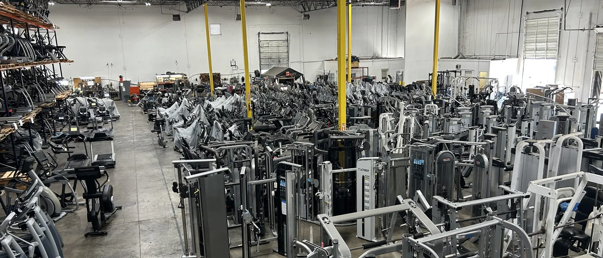 Rows of pre-owned commercial fitness equipment in the DOF warehouse
